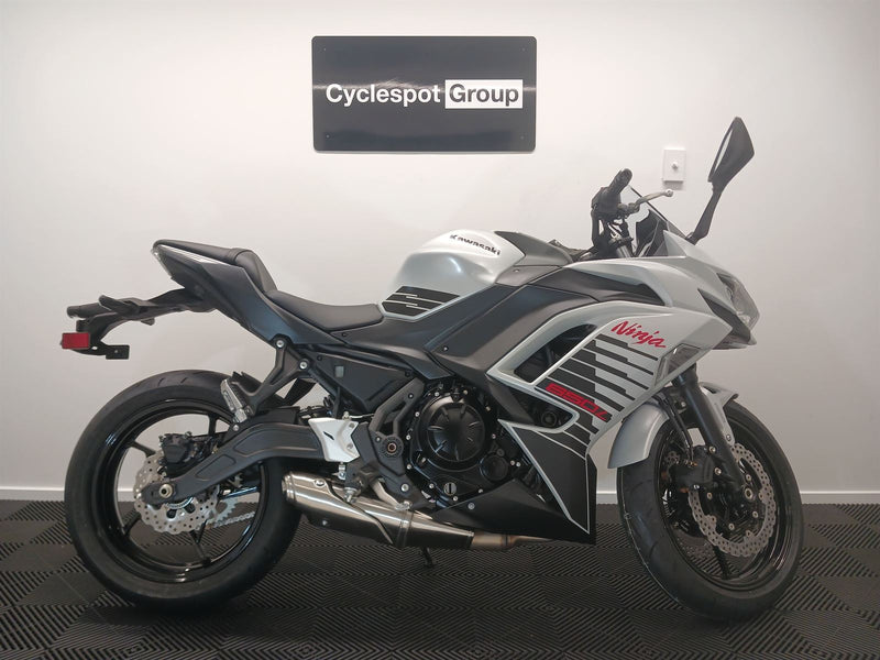Load image into Gallery viewer, 2026 Kawasaki Ninja ER 650 F in Pearl White on display with 'Cyclespot Group' sign in the background