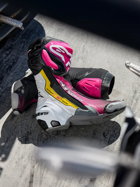 Alpinestars Supertech R motorcycle racing boots in a striking pink, white, and yellow colourway, featuring professional-grade ankle protection and ventilated shin plates, available at Cyclespot New Zealand.
