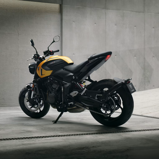 A black and yellow 2026 Triumph Trident 660 LAMS motorcycle parked on a concrete surface against a textured gray concrete wall.